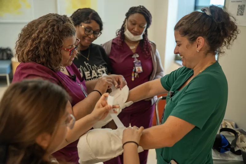 Healthcare staff in scrubs collaborating during a hands-on training exercise, examining medical equipment together.
