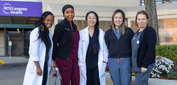 Five female NYU Langone Hospital—Brooklyn staff members stand together smiling for a photo outside the hospital.