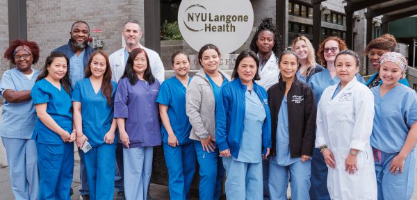 A diverse group of NYU Langone Orthopedic Hospital staff pose for a photo outside the hospital.