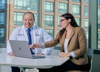 A male physician and a female staff member at NYU Grossman Long Island School of Medicine work together on a laptop.