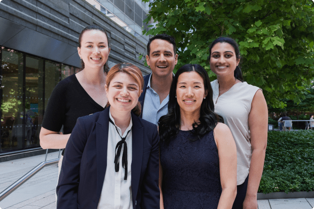 Five staff members stand together, smiling for a photo in an outdoor setting.