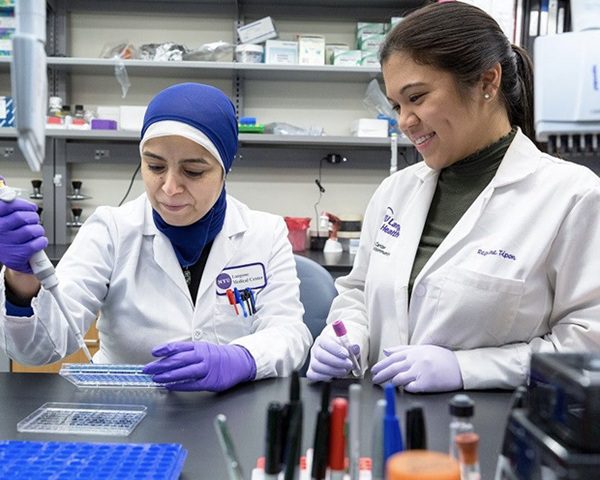 Two female research staff members work together in a laboratory setting.